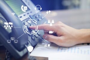 A man’s hand using a phone that is connected to a cloud-based phone system 