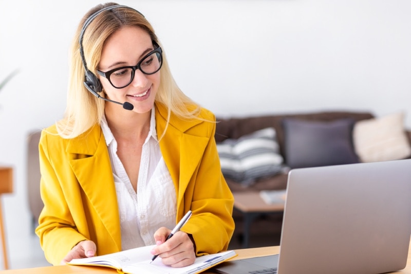 A human woman poses with a virtual receptionist system